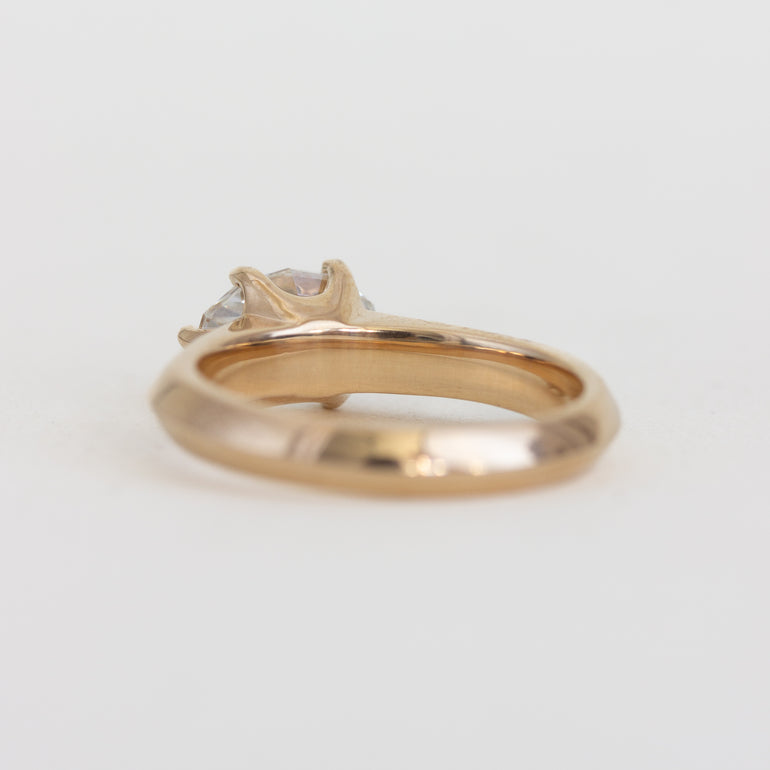 Gold ring with a diamond on a light gray background