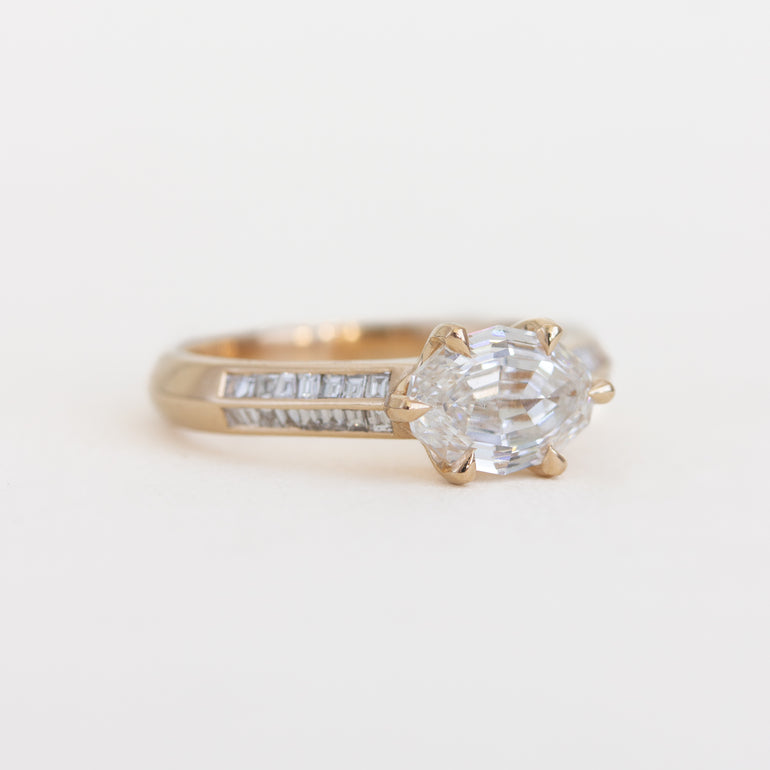 Gold ring with a large diamond and smaller diamonds on a light background
