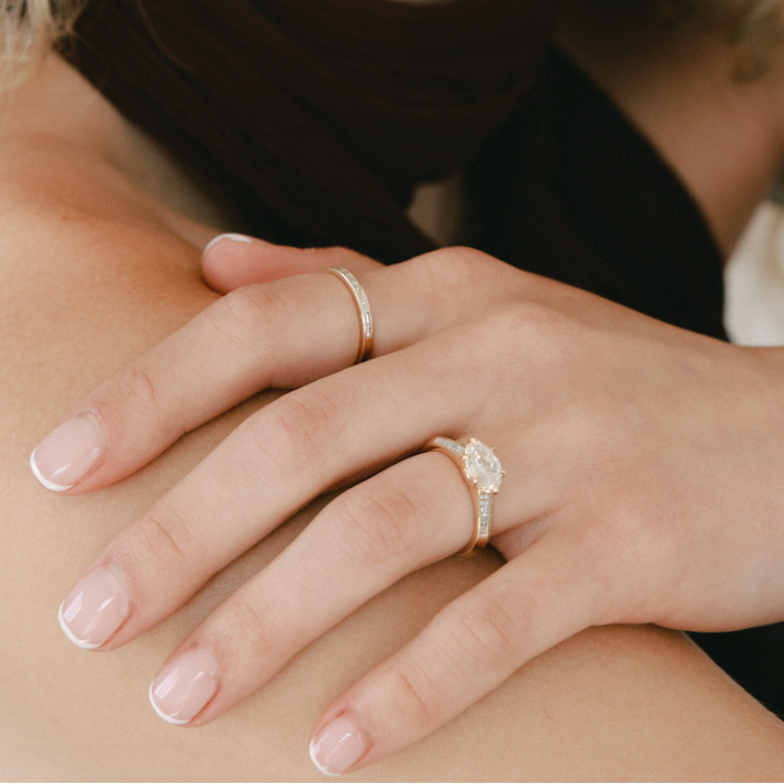 Close-up of a woman with a ring on her finger, wearing a black top.