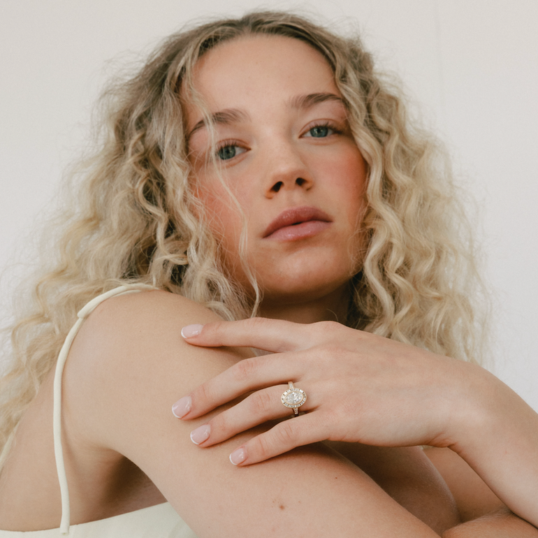 Woman with curly hair wearing a white top against a plain background