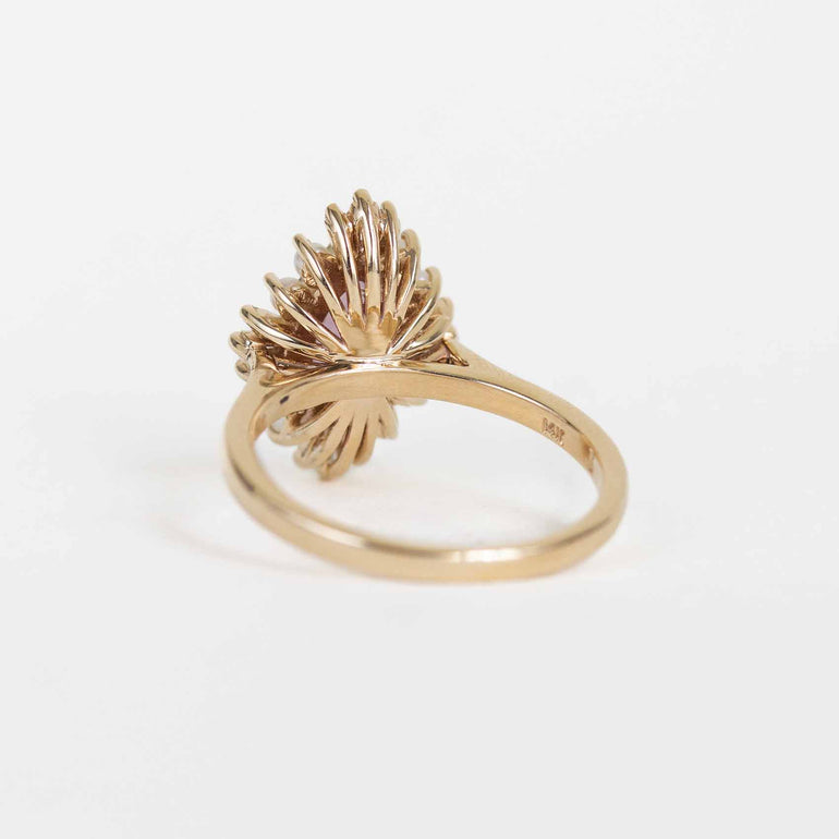 A gold ring with a textured, fan-like or sunburst-shaped top, photographed on a clean white background.
