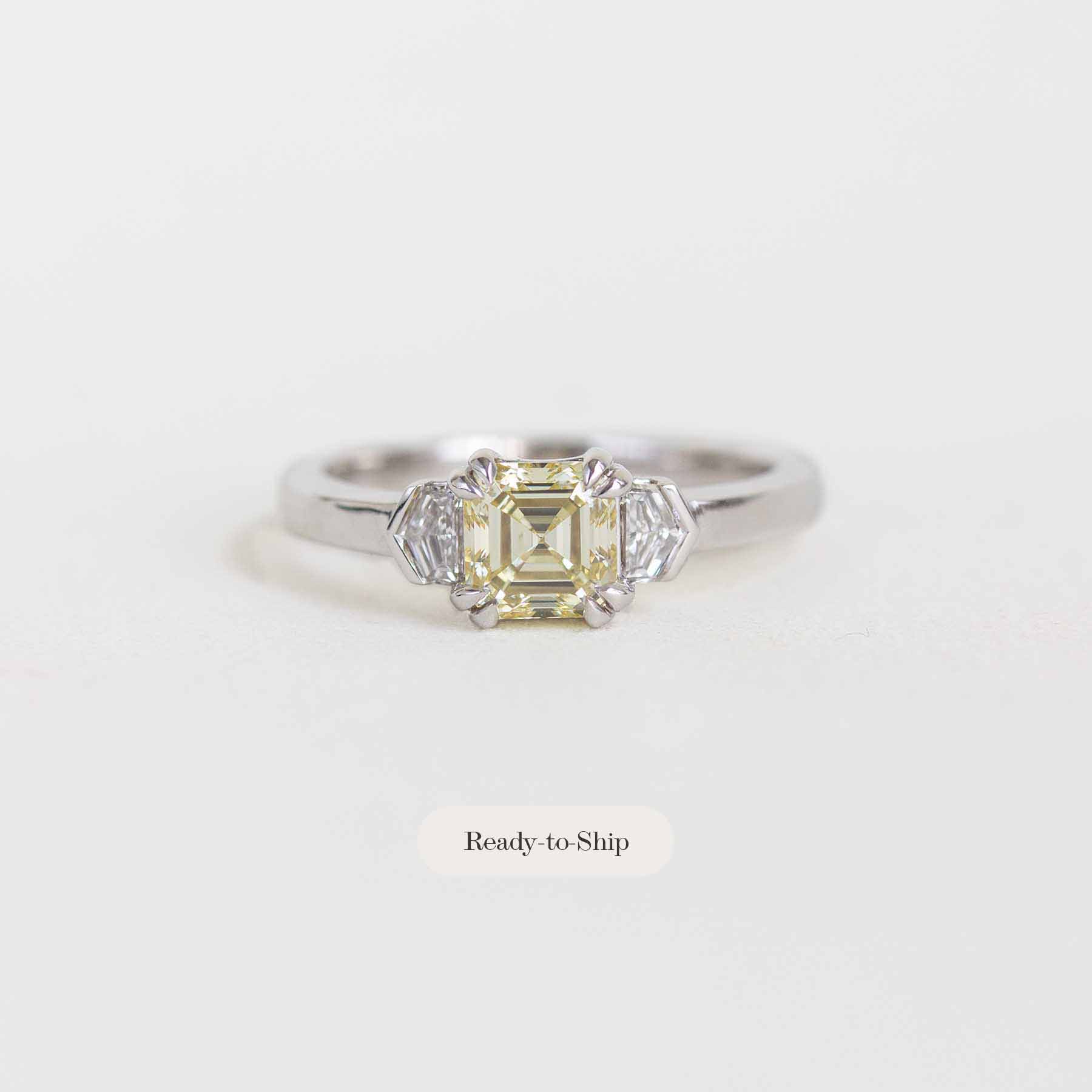 A yellow emerald-cut diamond engagement ring in a silver-toned setting with accent diamonds, shown on a light gray background with a 'Ready-to-Ship' label below.