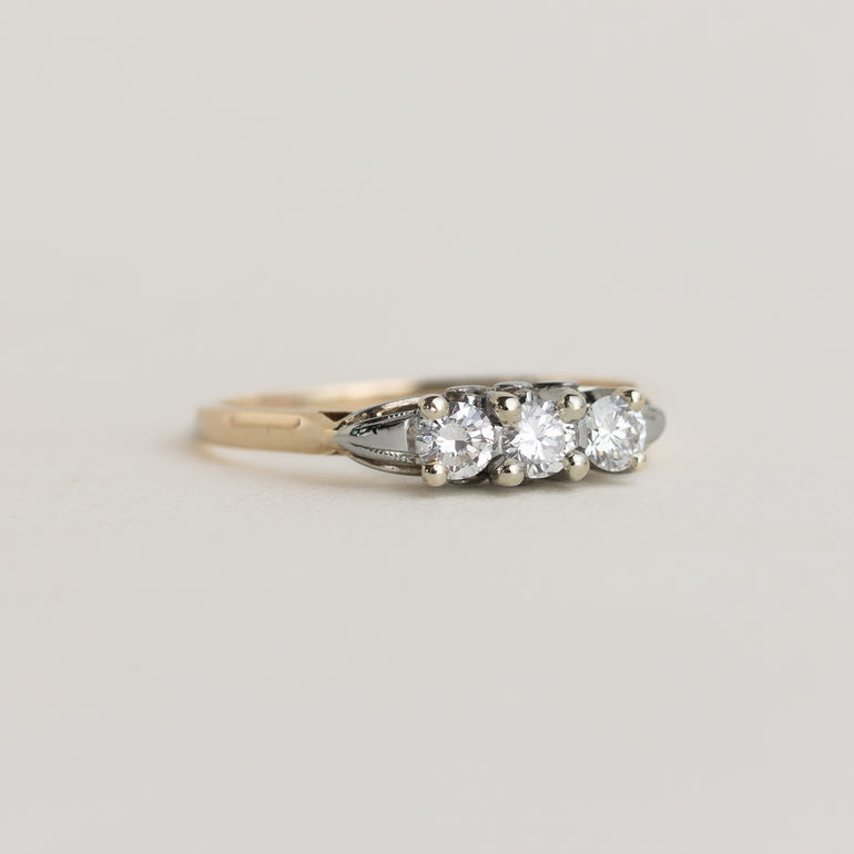 Three-stone diamond ring on a light gray background