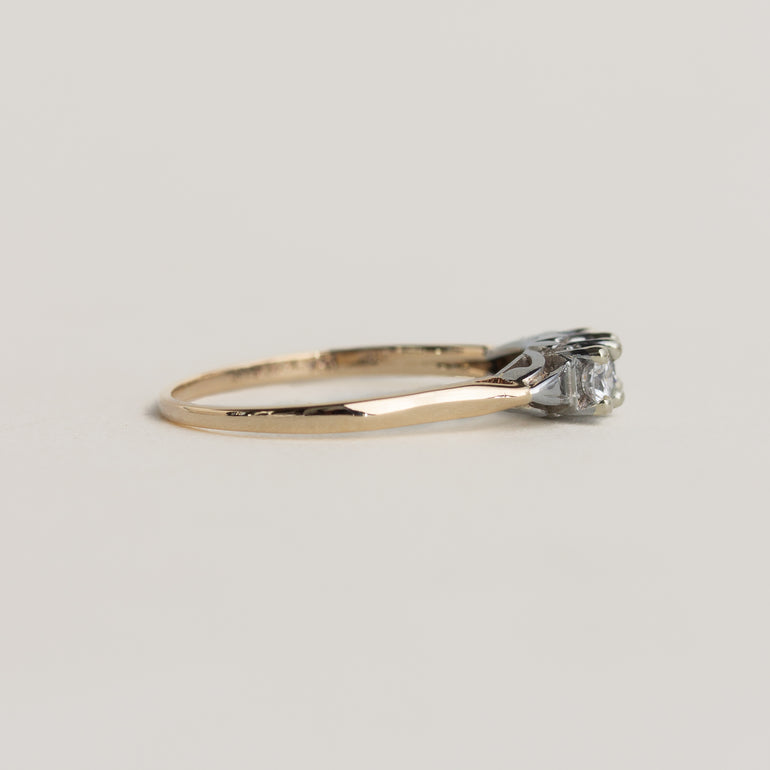 Gold ring with a diamond on a light gray background
