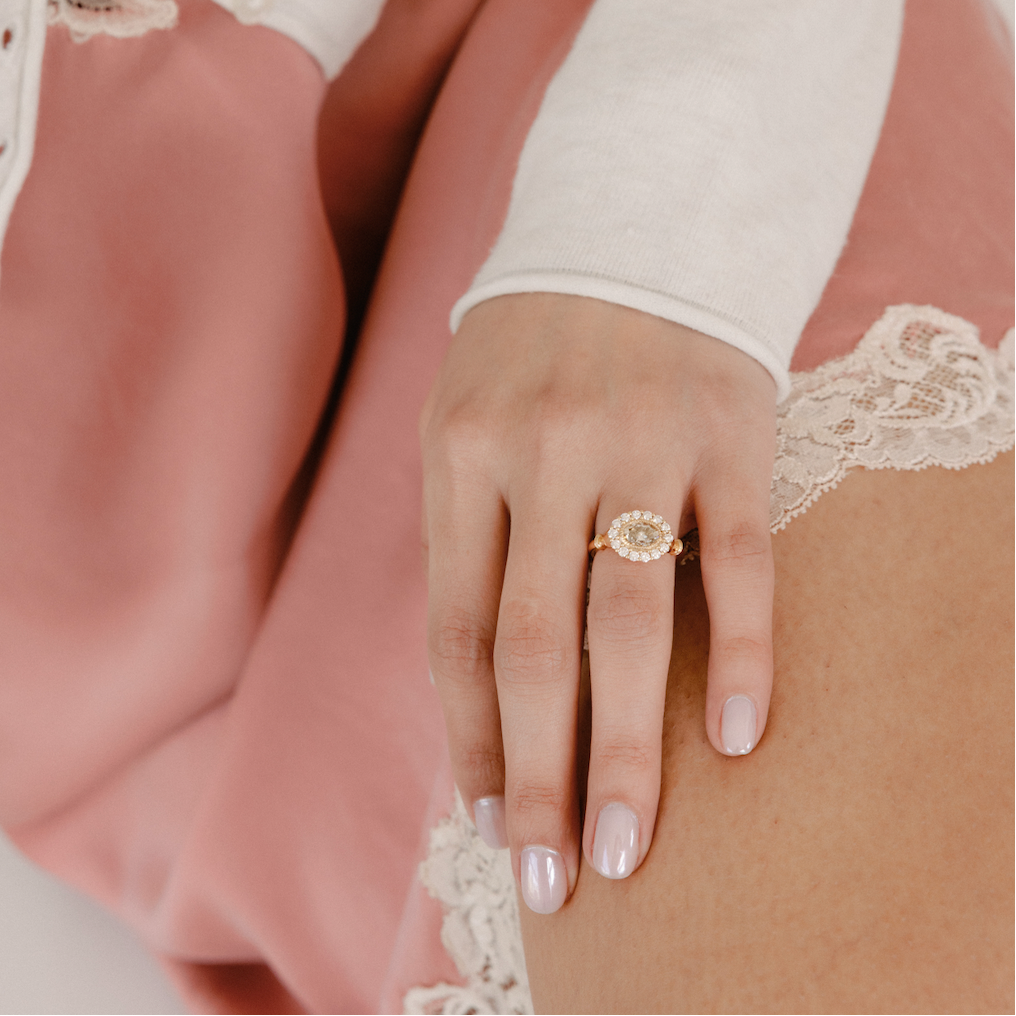 Close-up of a hand wearing a gold ring with a white lace glove and pink dress.