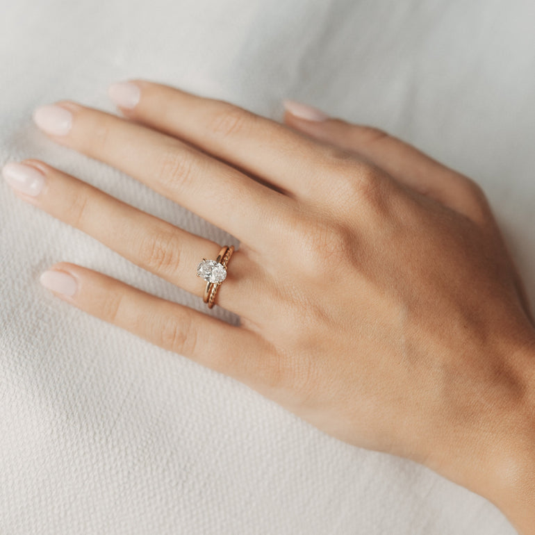 braid twist wedding band on models hand with solitaire engagement ring