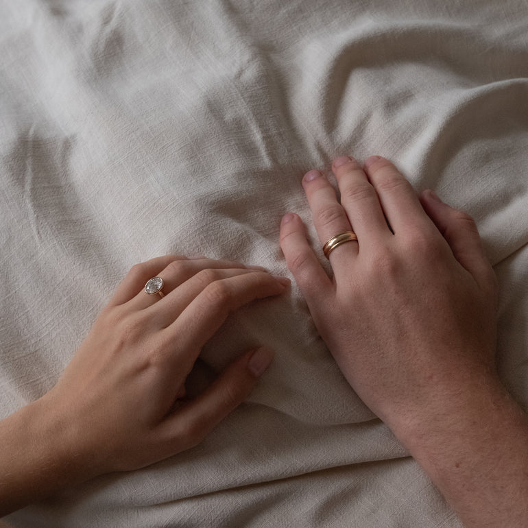 wide cigar band with line detailing on models hand and diamond engagement ring on other hand