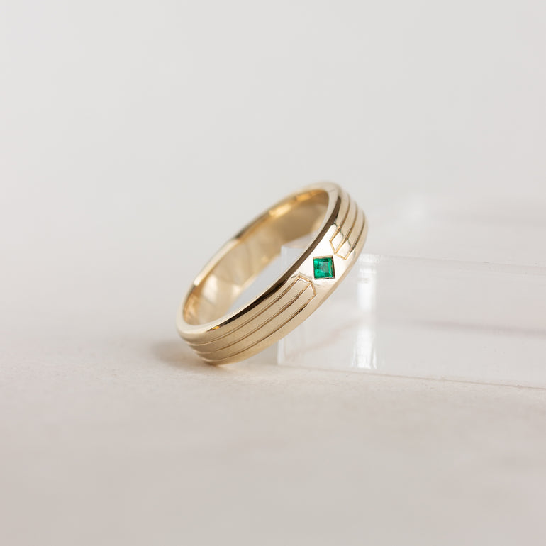 etching detail flush set stone wedding band with emerald set in