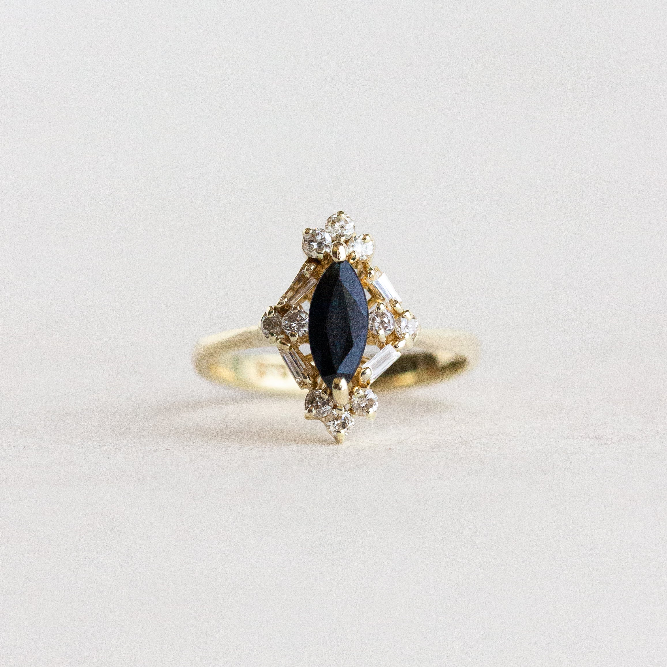 Gold ring with a black gemstone and diamonds on a light gray background