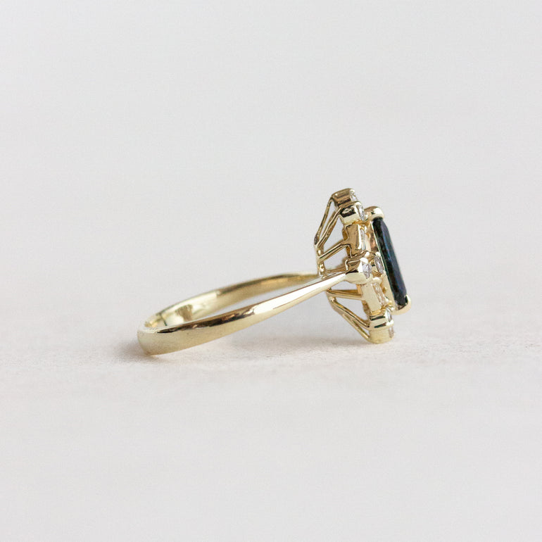 Gold ring with a blue gemstone on a light gray background
