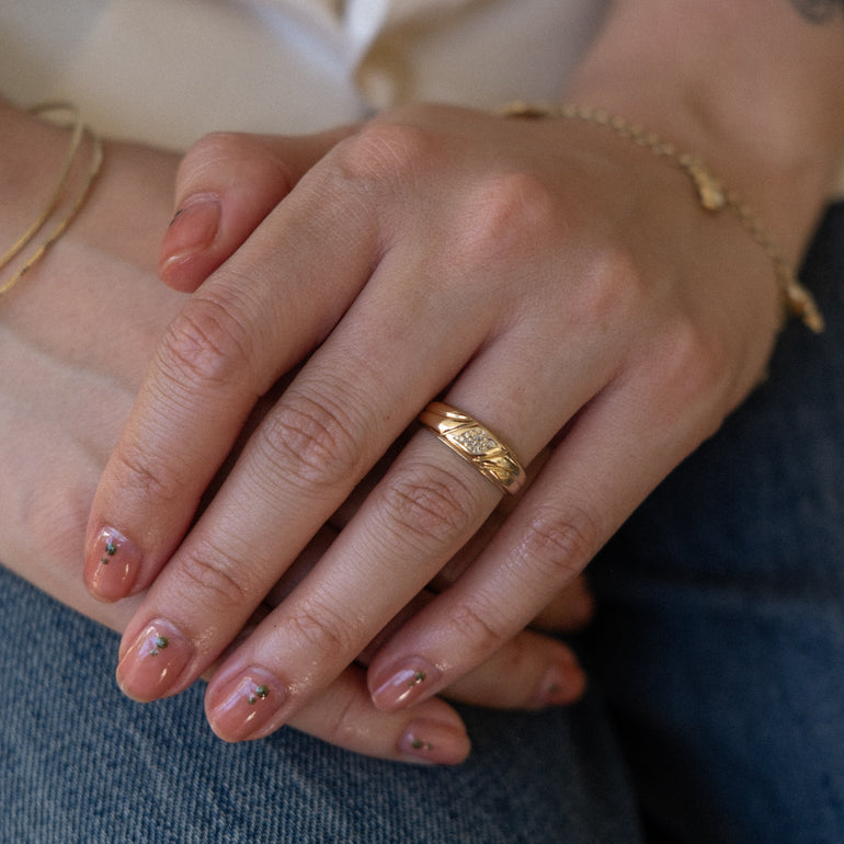 Close-up of a hand wearing a gold ring with a blurred background