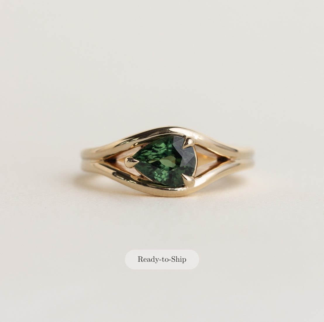 14K gold Lola ring with an east-west pear shaped, medium-green sapphire