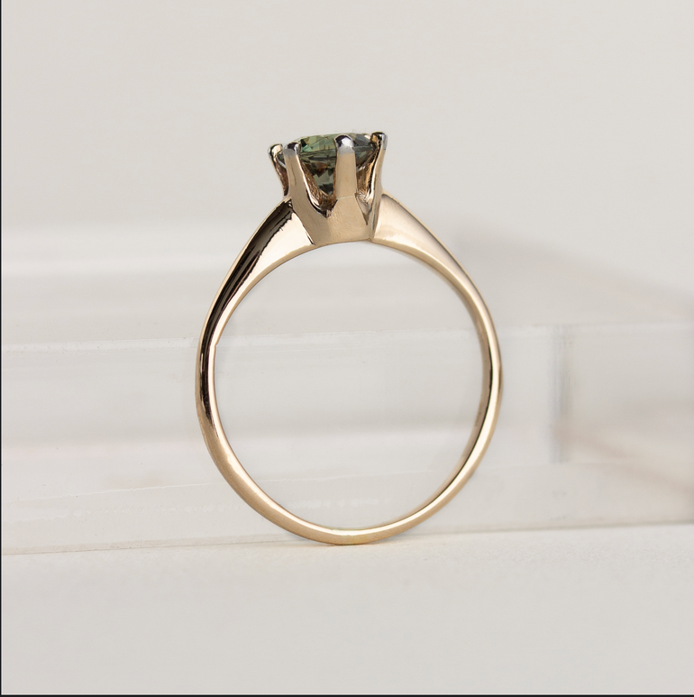 Gold ring with a diamond on a light gray background