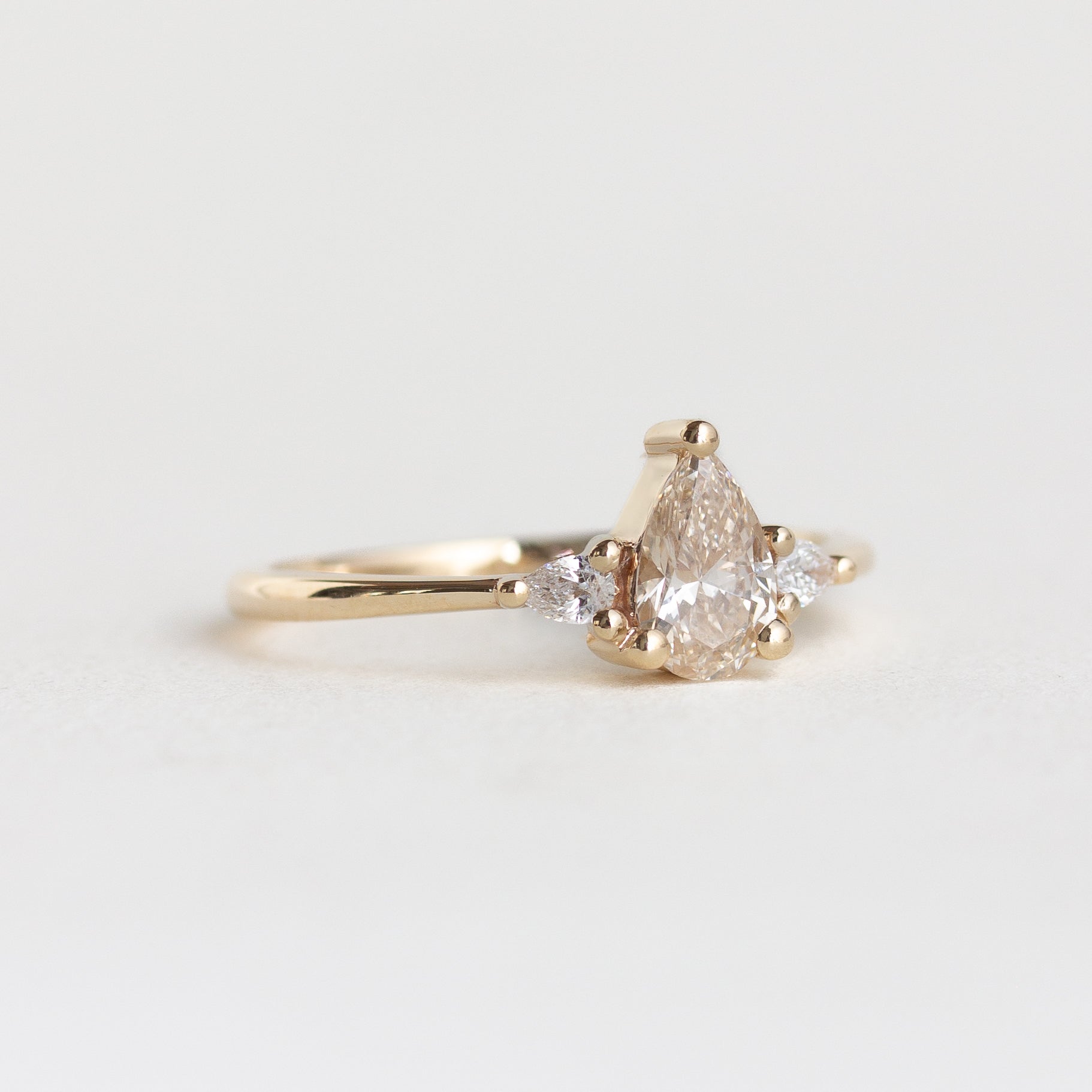 14k gold pear, three stone Marie ring with a champagne diamond