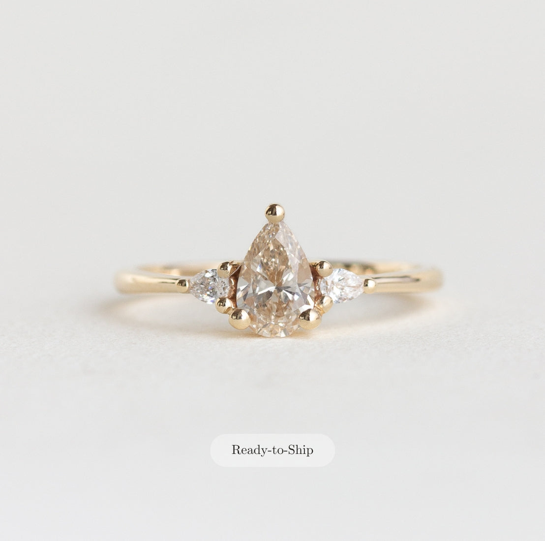 14k gold pear, three stone Marie ring with a champagne diamond