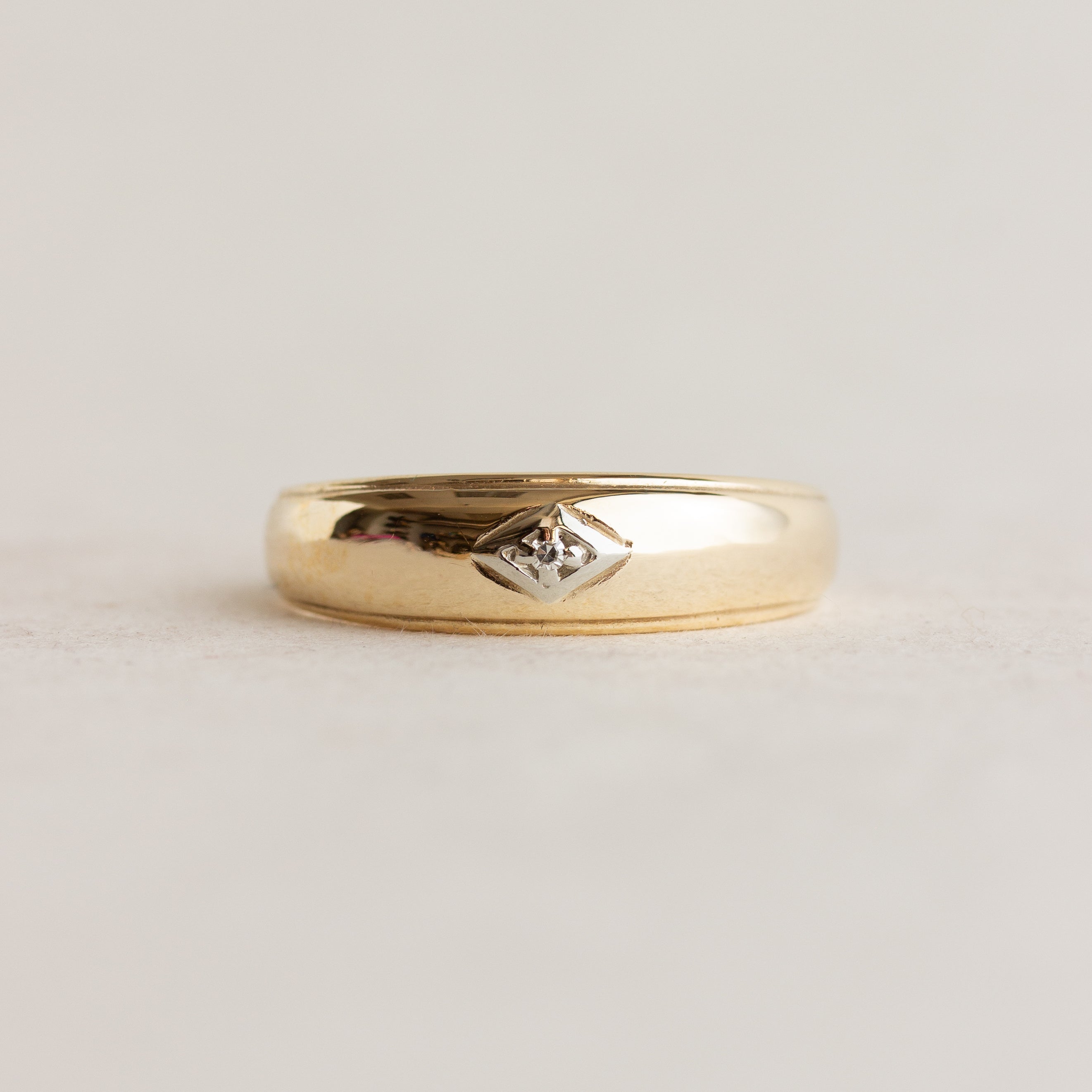 Gold ring with a diamond on a light gray background