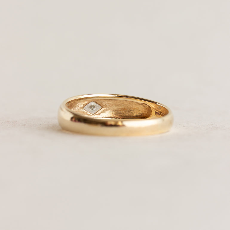 Gold ring with a diamond on a light gray background