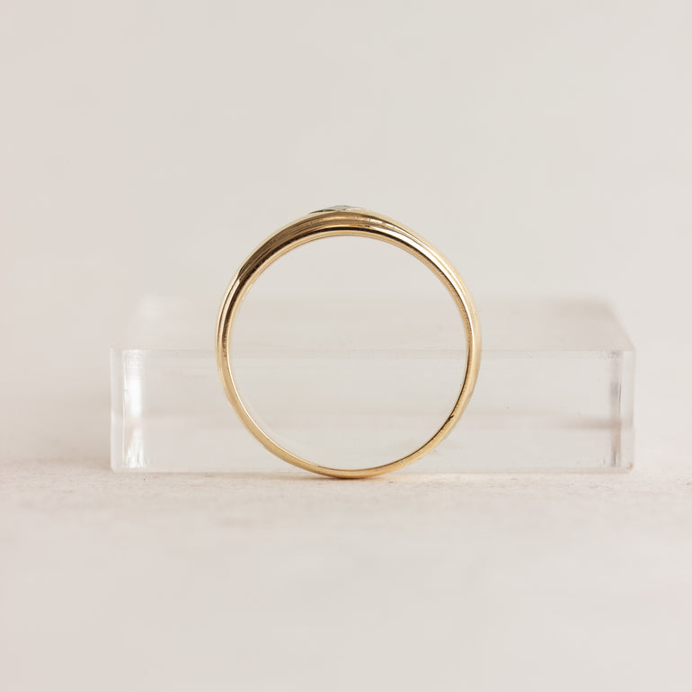 Gold ring on a clear stand against a light beige background