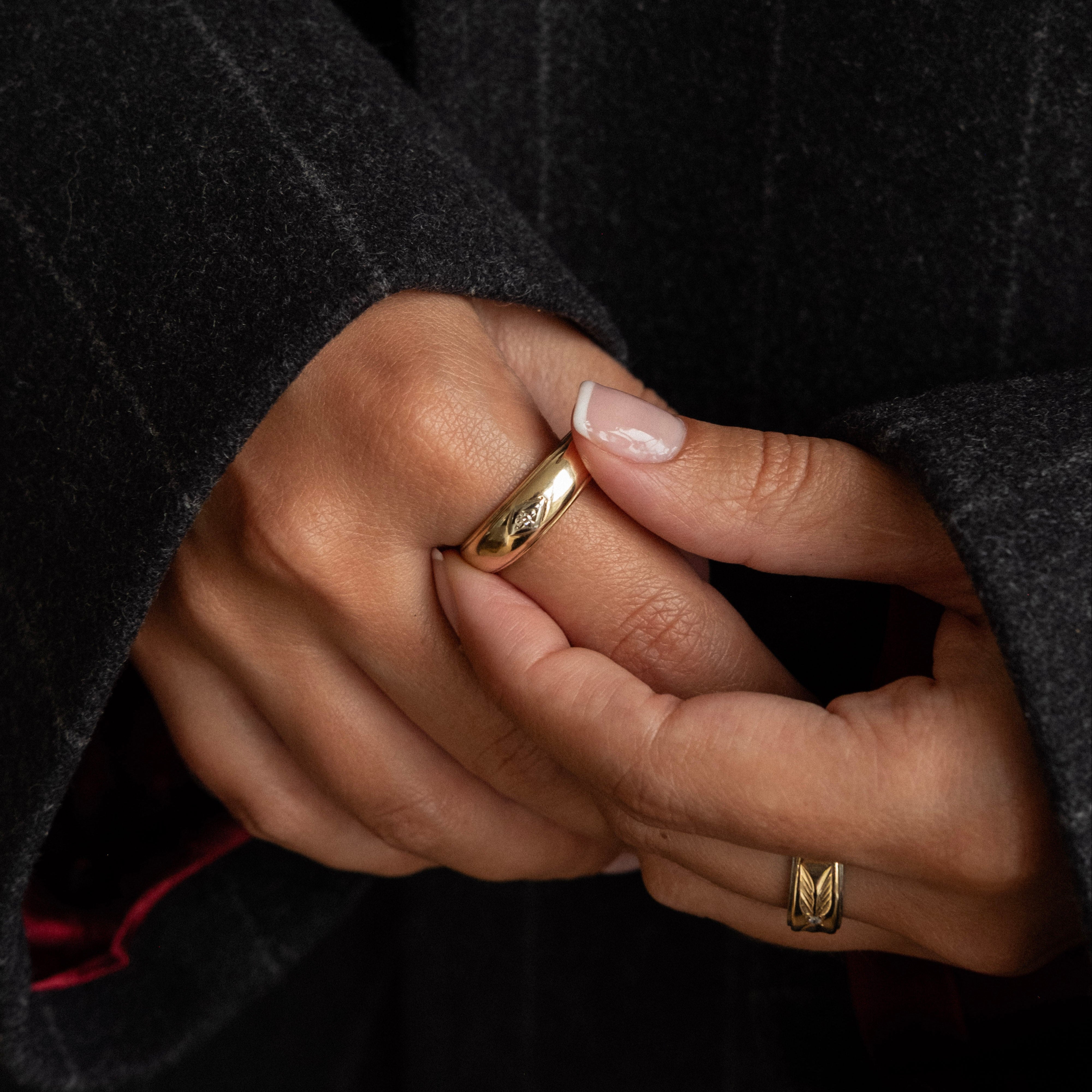 Close-up of hands with gold rings against a dark background