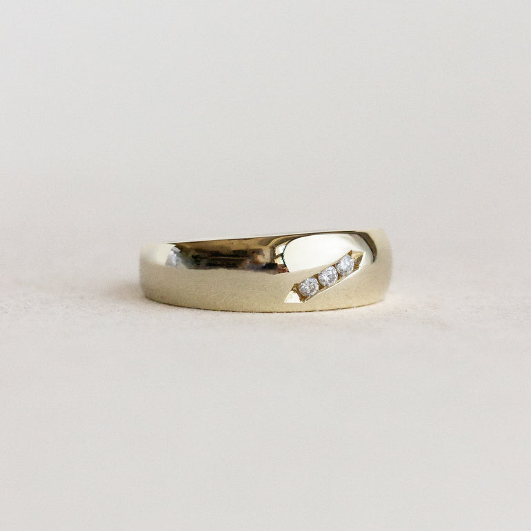 Gold ring with embedded diamonds on a light gray background