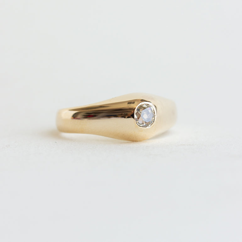Gold ring with a diamond on a light gray background