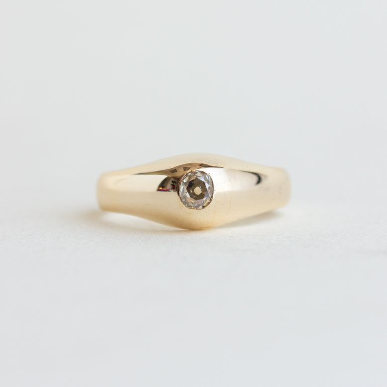 Gold ring with a diamond on a light gray background