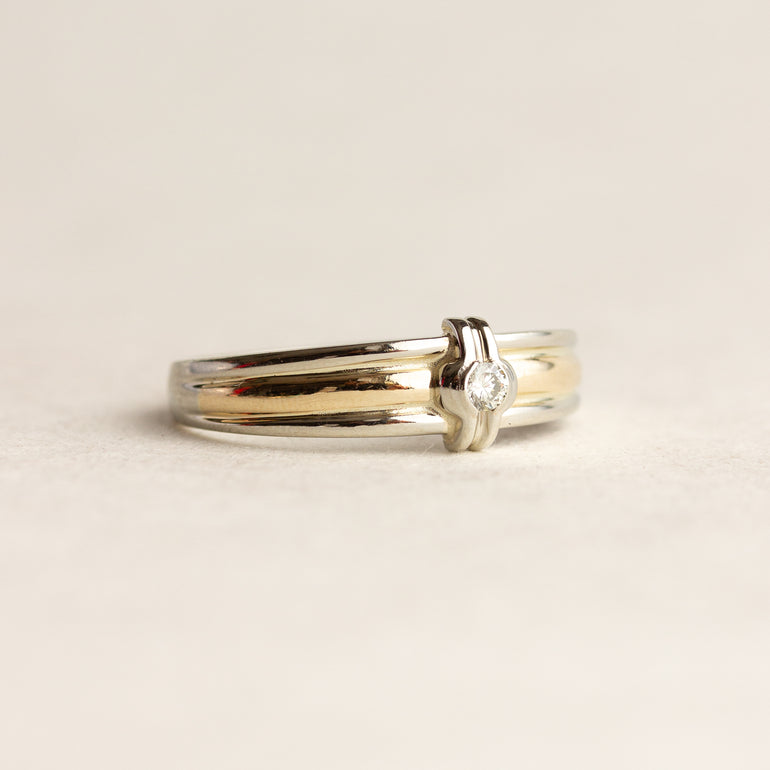 Two-tone ring with a diamond on a beige background