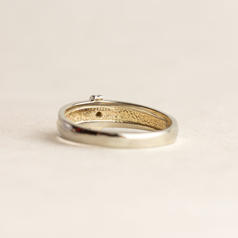 Gold ring with intricate design on a beige background