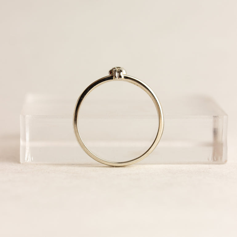 Gold ring on a clear stand against a beige background