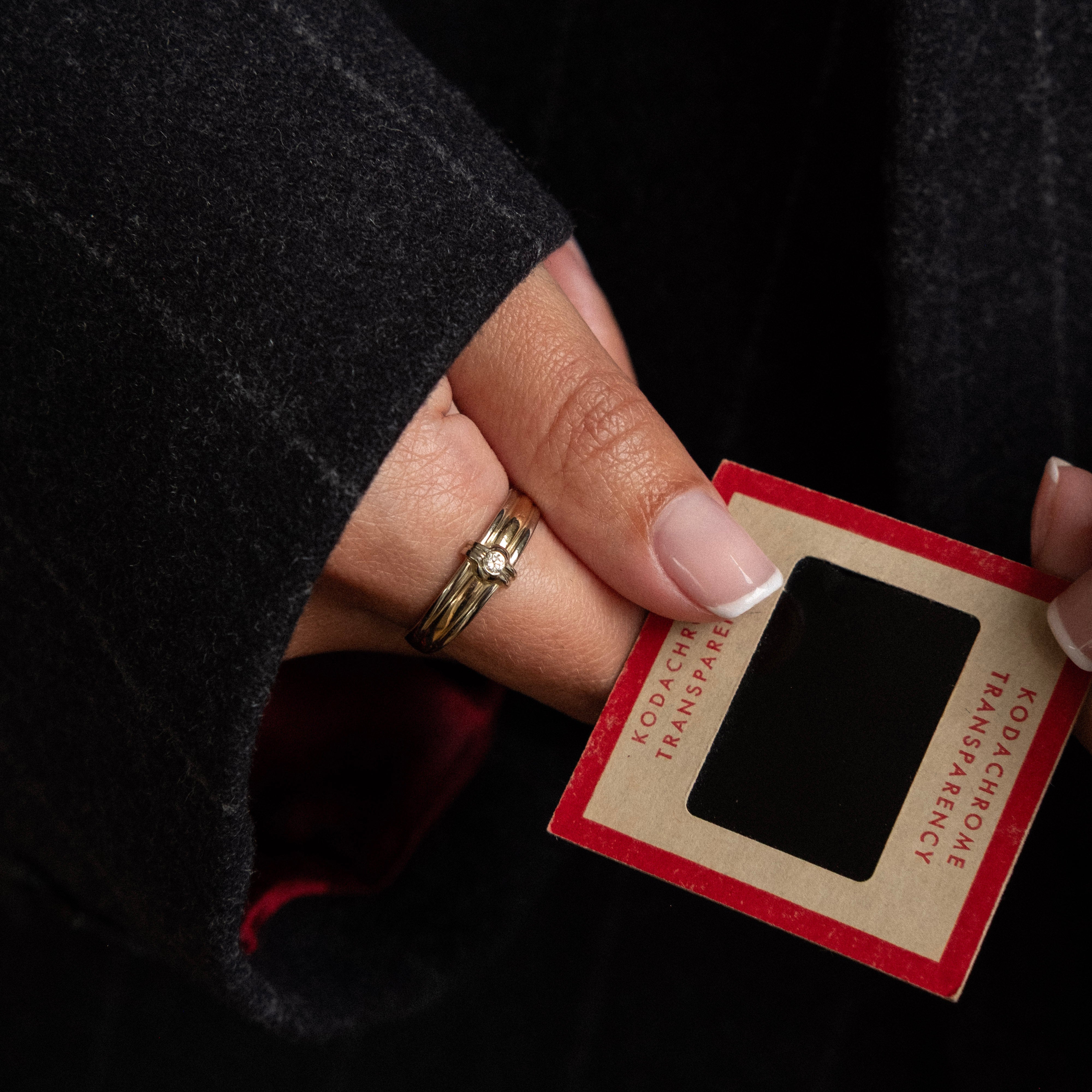 Hand holding a small red and beige card with text, against a dark background