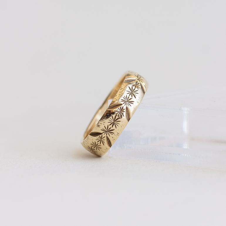 Gold ring with intricate patterns on a light gray background