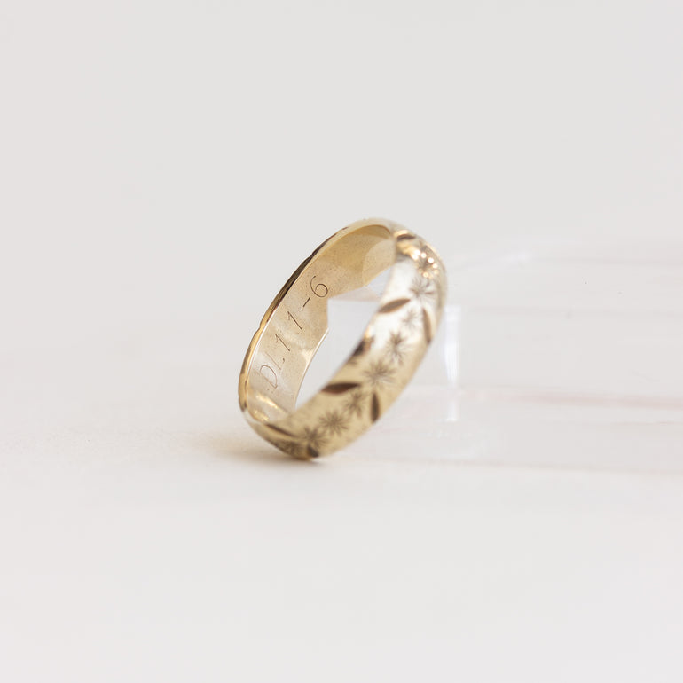 Gold ring with engraved text on a light gray background