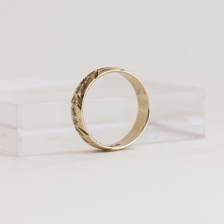 Gold ring with intricate design on a white background