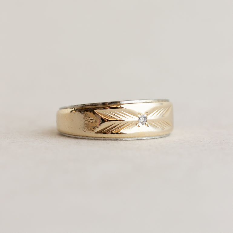 Gold ring with a diamond on a light gray background