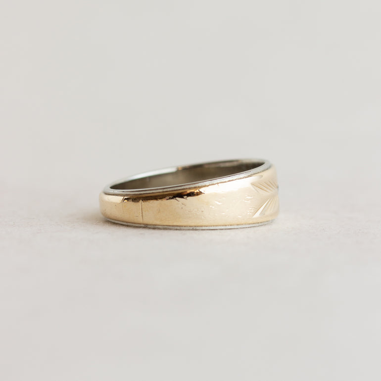 Gold ring with a textured band on a light gray background