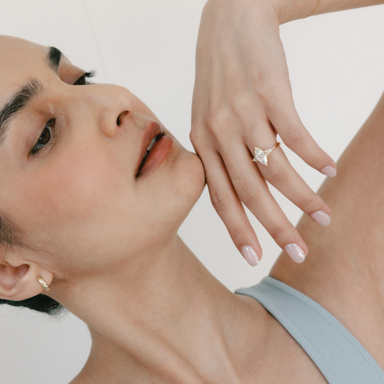 Woman wearing a diamond ring on her hand with a plain background