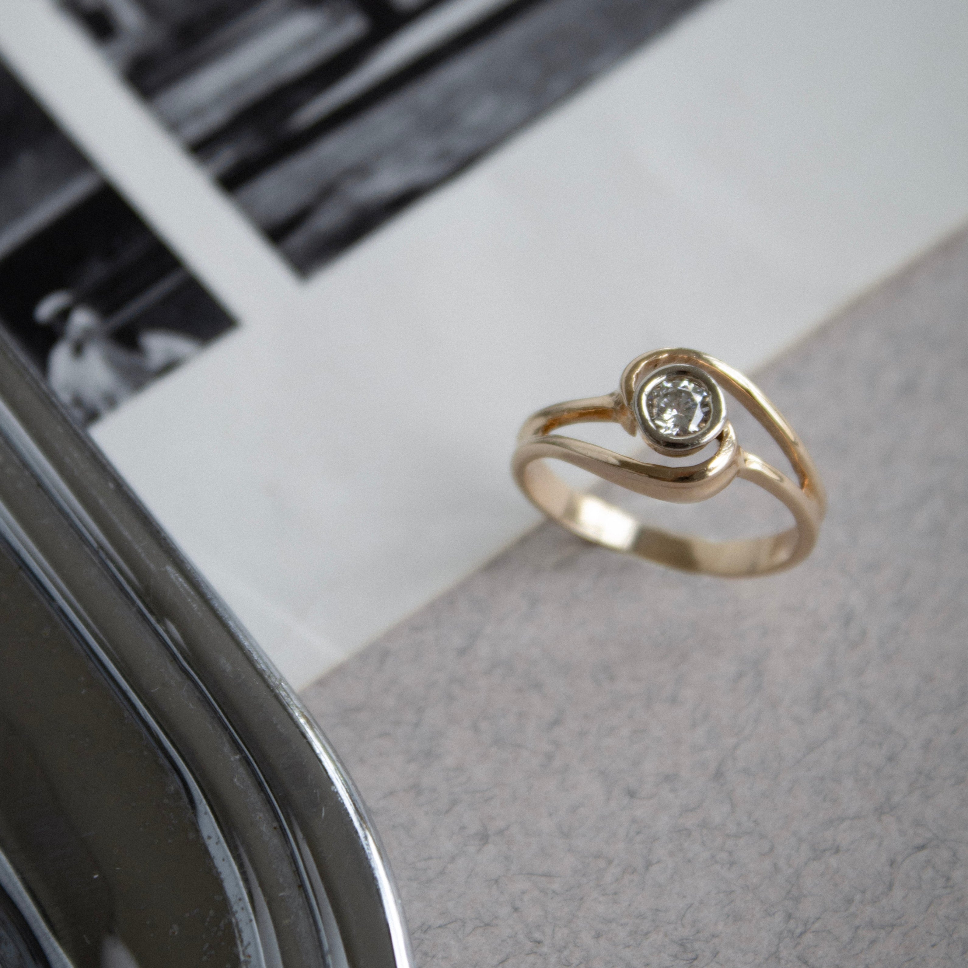 Gold ring with a diamond on a textured surface with a blurred background