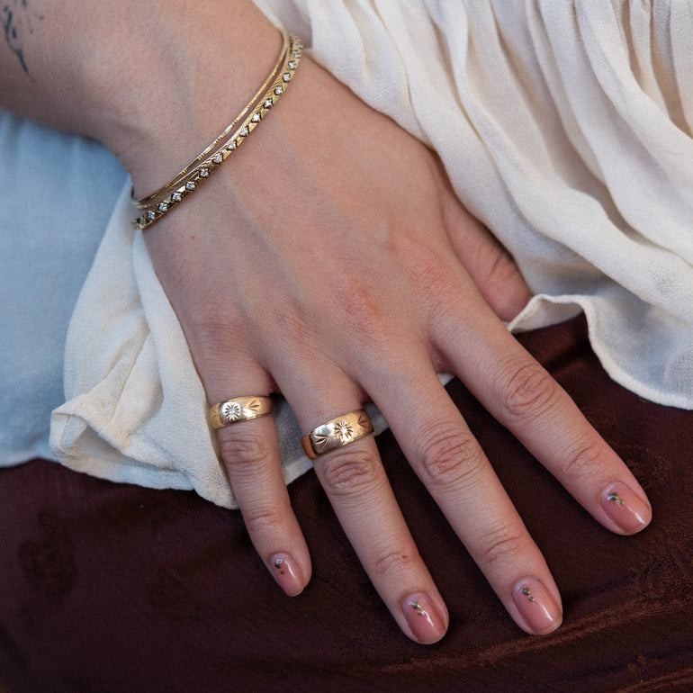 Hand with gold rings and bracelet on a neutral background